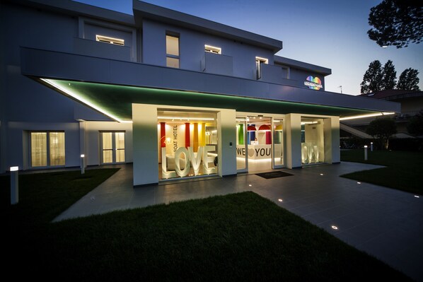 A modern hotel with a glass facade, illuminated signage, and a welcoming entrance. - Love Boat (Riccione)