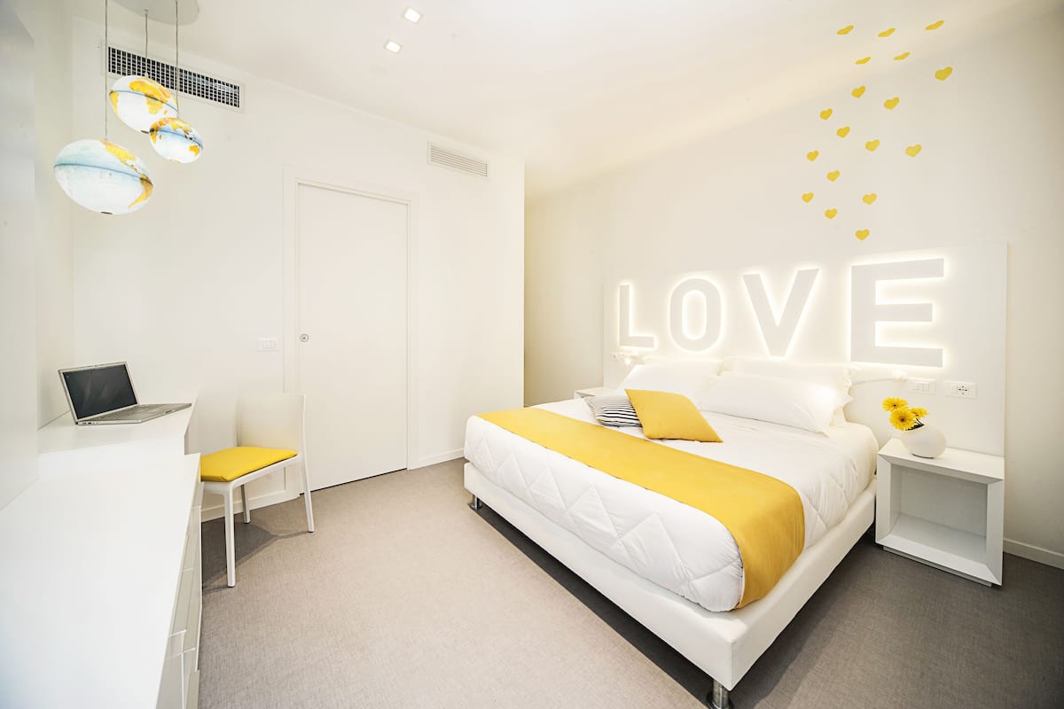 A modern hotel room with a bed, a desk, and a chair.
