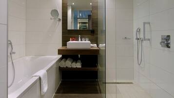 A modern bathroom with a bathtub, a glass-enclosed shower, and a vanity with a mirror.