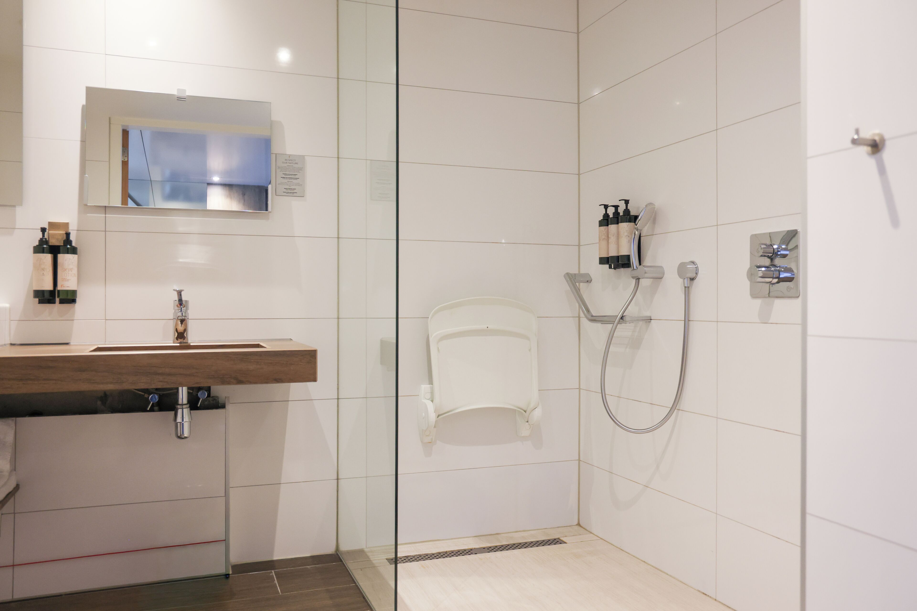 Une salle de bain moderne équipée d’un lavabo, d’un miroir, d’une douche et d’articles de toilette.