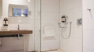 Une salle de bain moderne équipée d’un lavabo, d’un miroir, d’une douche et d’articles de toilette.