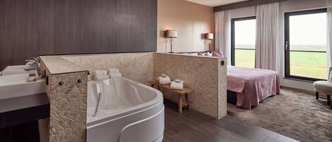 A modern bathroom with a large bathtub, two sinks, a vanity, and a view of the outdoors through a sliding door.