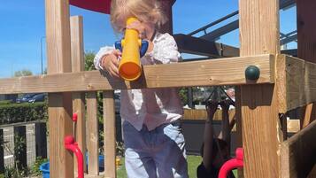 A wooden play structure with a red slide and a yellow telescope.