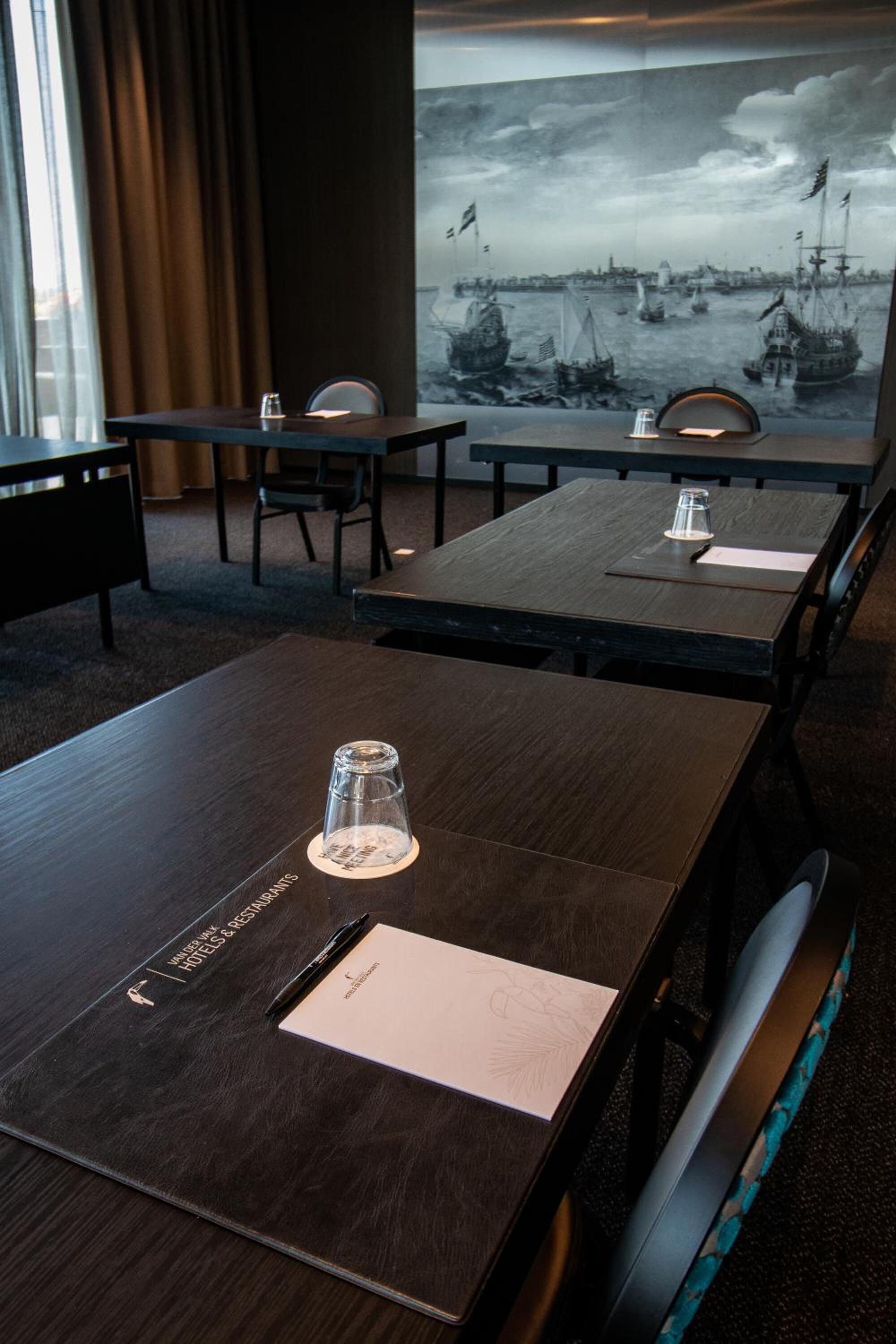 A conference room with a large table, chairs, and a backdrop of a maritime scene.