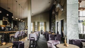 A modern restaurant interior with marble columns, plush seating, and a bar area.
