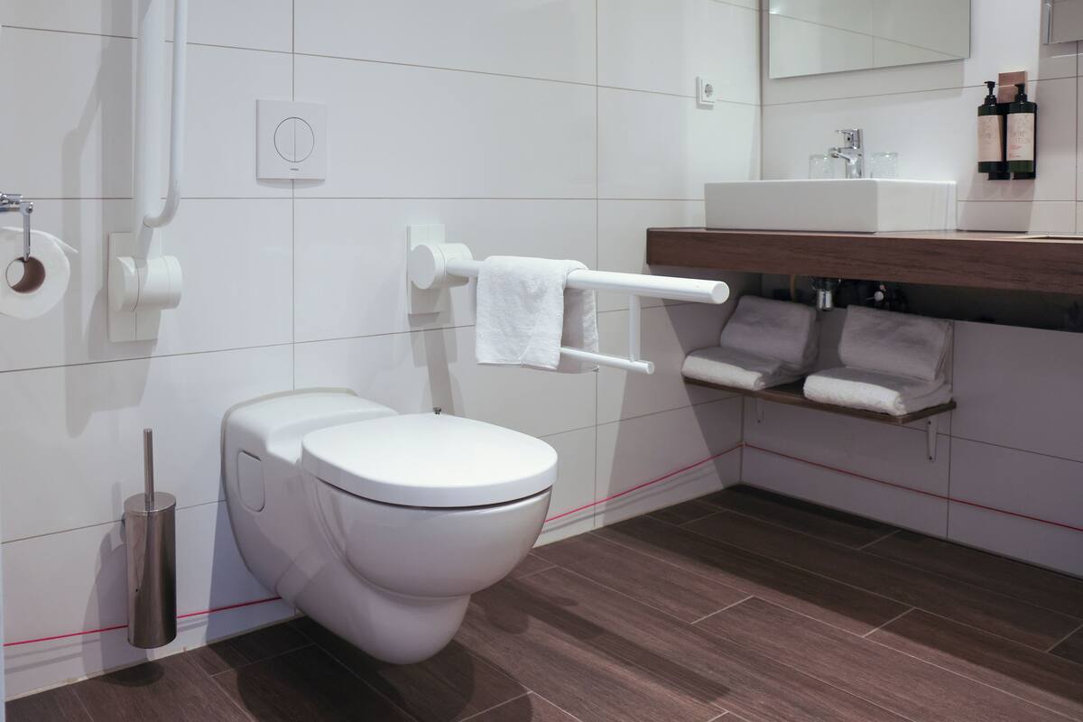 Ein modernes Badezimmer mit Toilette, Bidet, Handtuchhalter und einem Spiegel über dem Waschbecken.