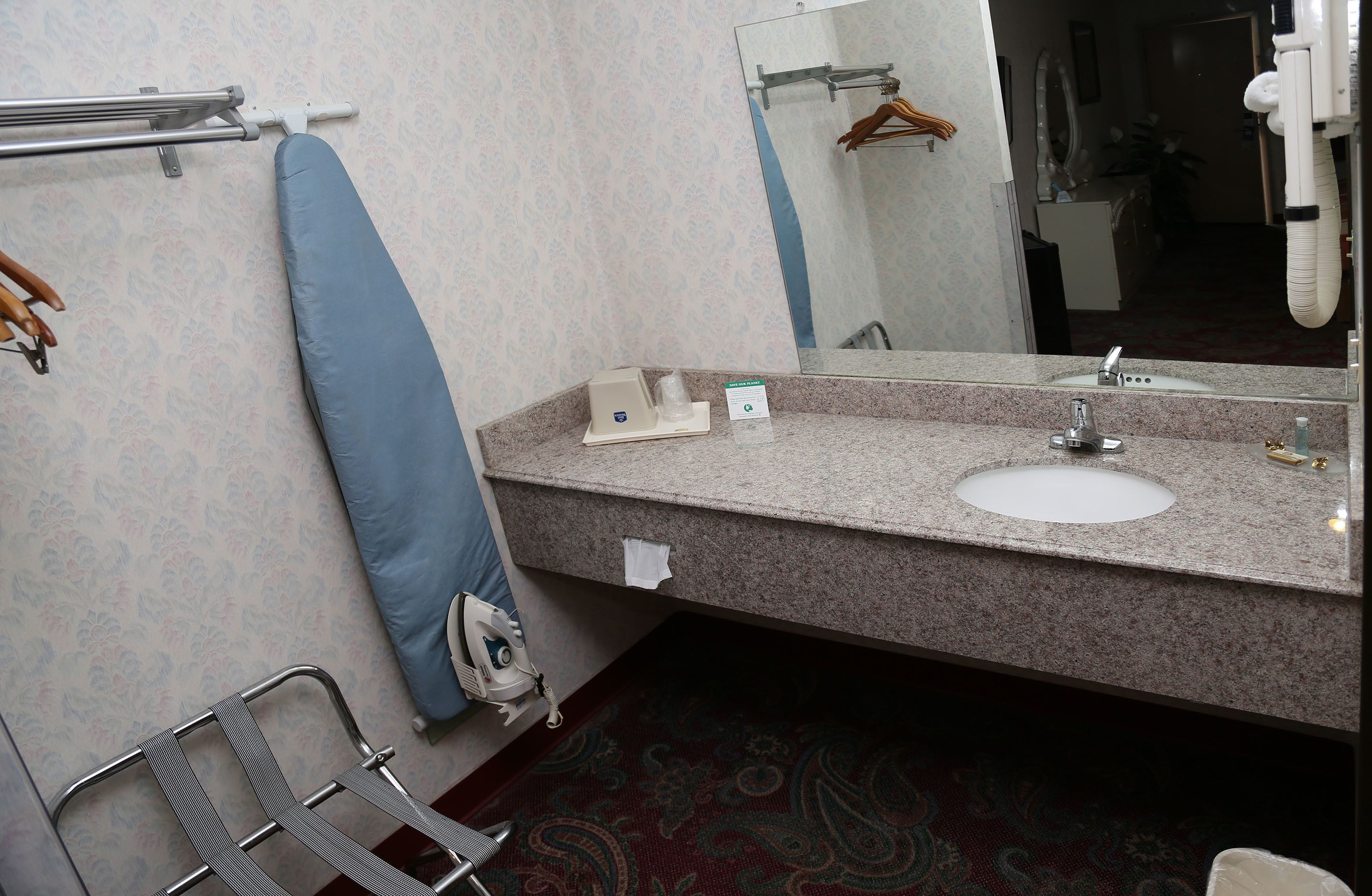 A bathroom with a sink, mirror, towel rack, and a chair.