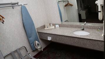 A bathroom with a sink, mirror, towel rack, and a chair.