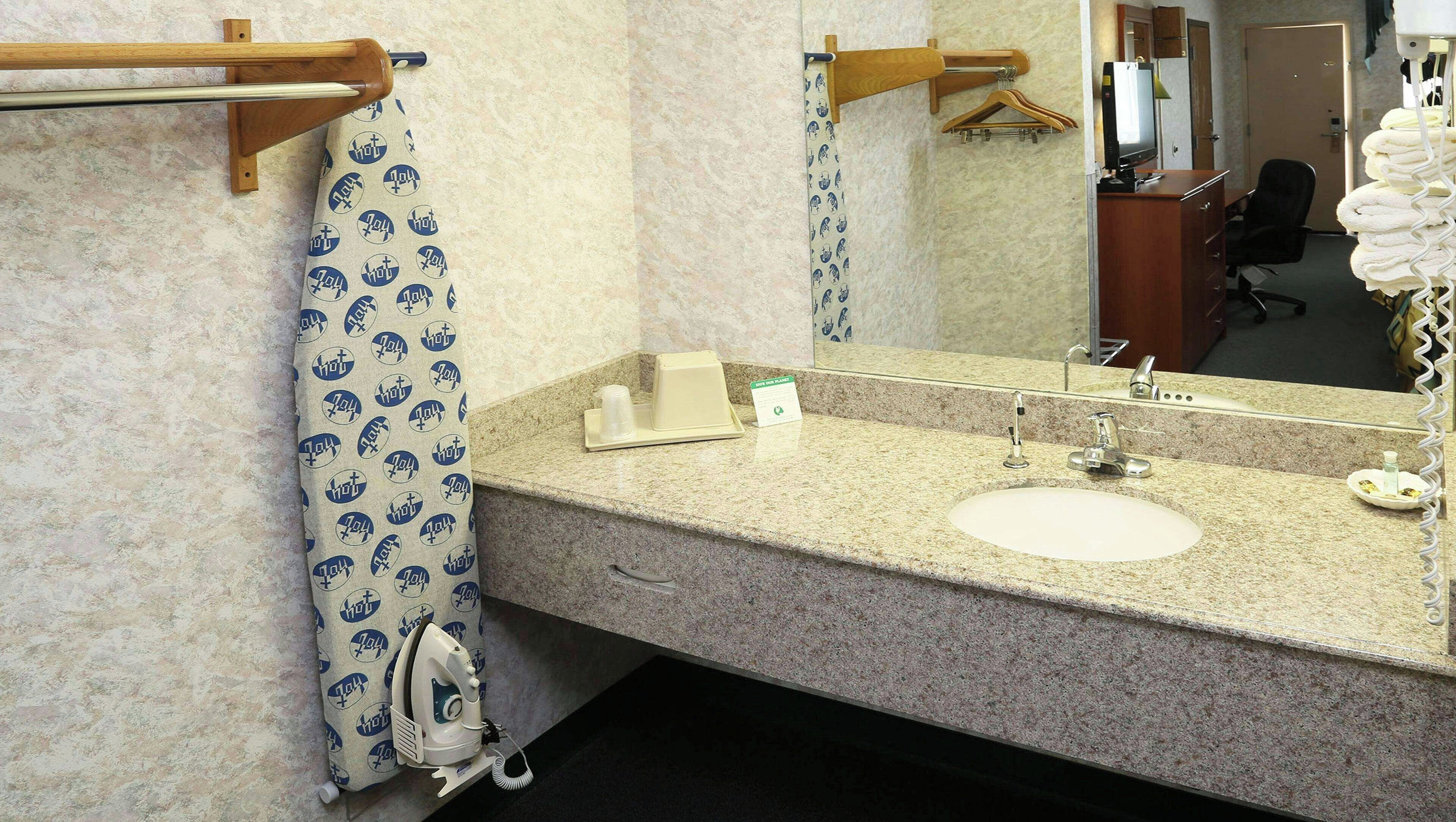 Un baño con lavamanos, espejo, toallero y cortina de ducha.