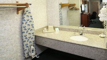 Un baño con lavamanos, espejo, toallero y cortina de ducha.