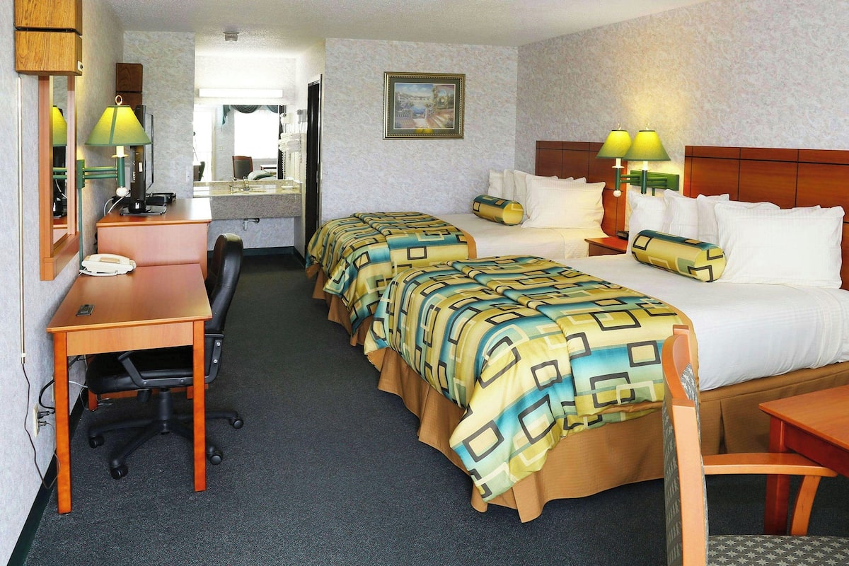 Habitación de hotel con dos camas, un escritorio, una silla, un teléfono y un espejo.