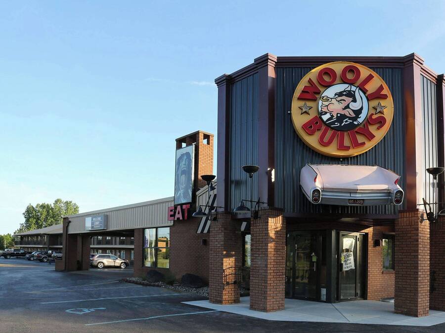 Un edificio con un llamativo letrero de 'Woolly Bulls', una entrada visible y un estacionamiento.