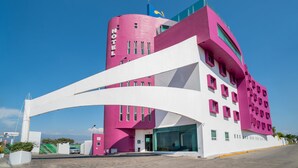A modern hotel with a pink and white color scheme, featuring a curved facade and multiple windows.