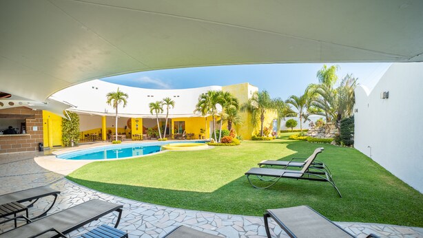 A pool area with lounge chairs, a swimming pool, and a covered patio.