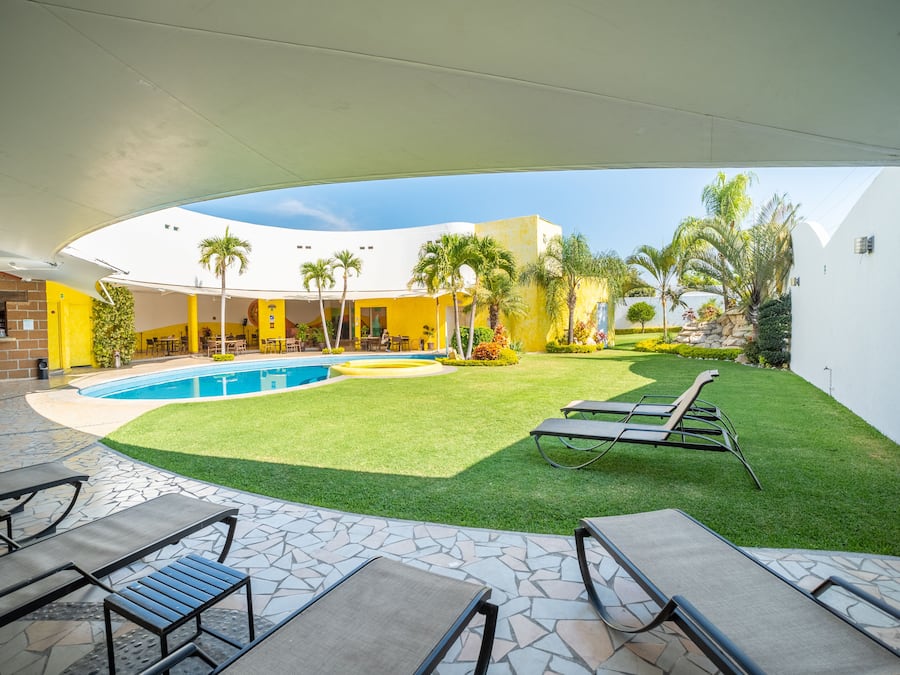 Alberca al aire libre, sombrillas en la alberca y camastros