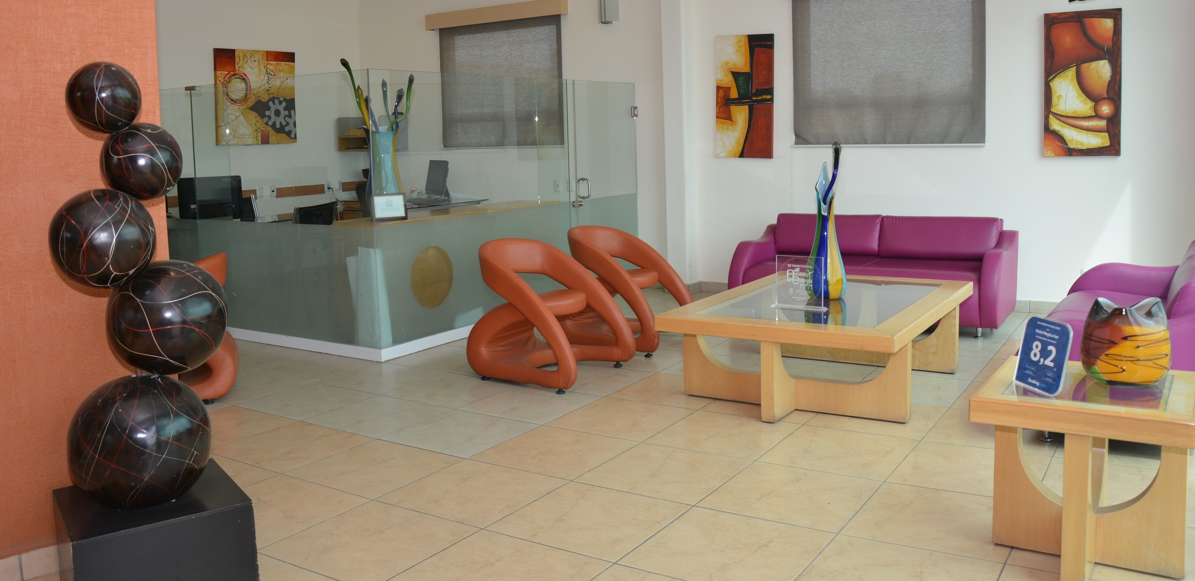 A reception area with a glass desk, orange chairs, a purple sofa, and abstract art on the walls.