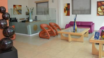 A reception area with a glass desk, orange chairs, a purple sofa, and abstract art on the walls.