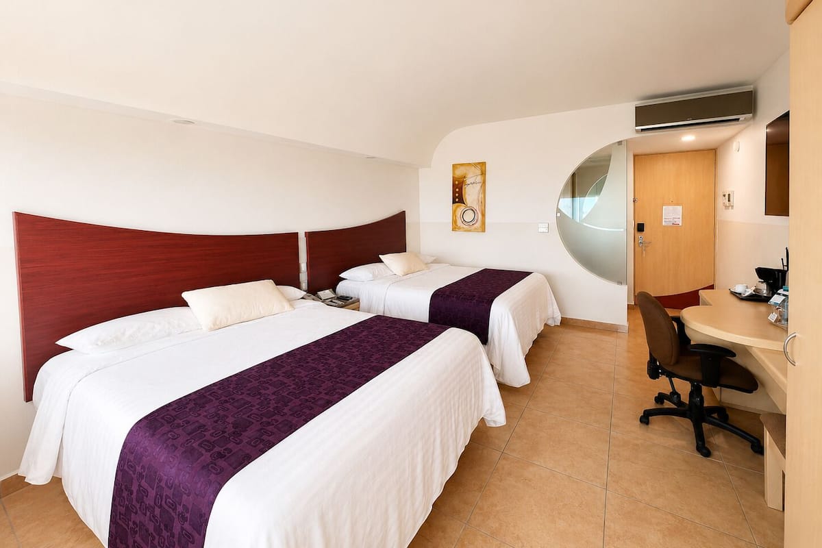 A hotel room with two beds, a desk, and a chair.