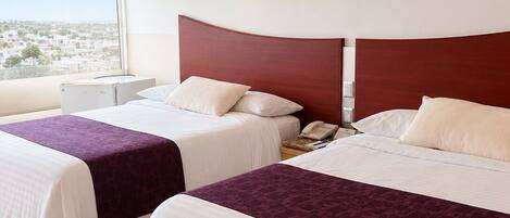 A hotel room with two beds, a nightstand, a telephone, and a window with a city view.