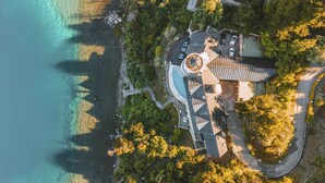 An aerial view of a coastal property with a circular building, a swimming pool, and a road leading to the entrance. - El Faro Boutique Hotel & Spa by DON (Villa La Angostura)