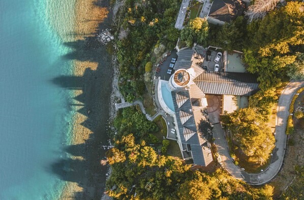 An aerial view of a coastal property with a circular building, a swimming pool, and a road leading to the entrance. - El Faro Boutique Hotel & Spa by DON (Villa La Angostura)