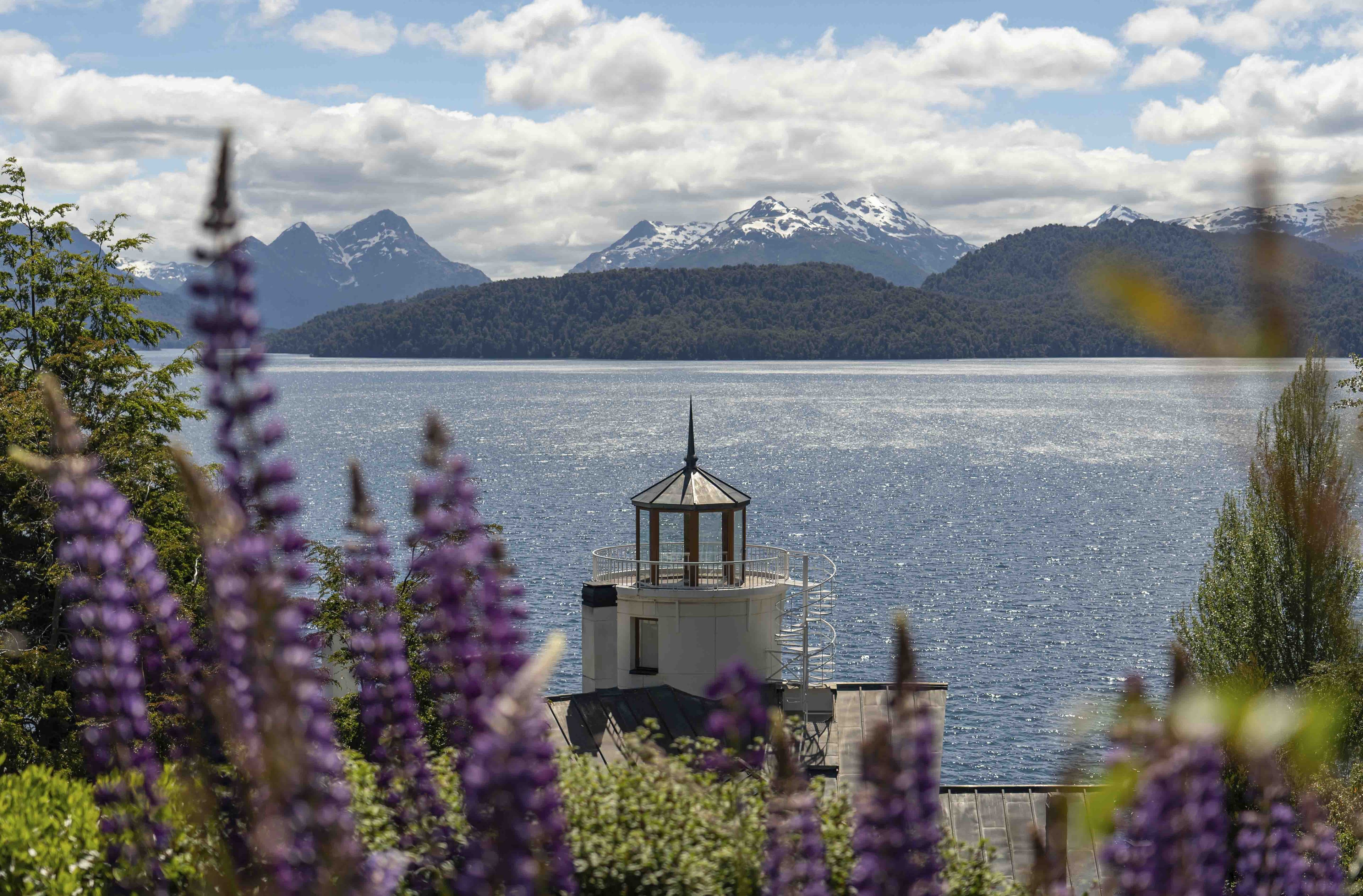 Un faro sobre un lago, con montañas al fondo.