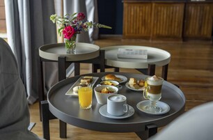 Desayuno con una bandeja que contiene un vaso de jugo de naranja, una taza de café, un vaso de leche y un postre.