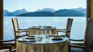 A dining table with chairs and a view of a lake and mountains. - El Faro Boutique Hotel & Spa by DON (Villa La Angostura)