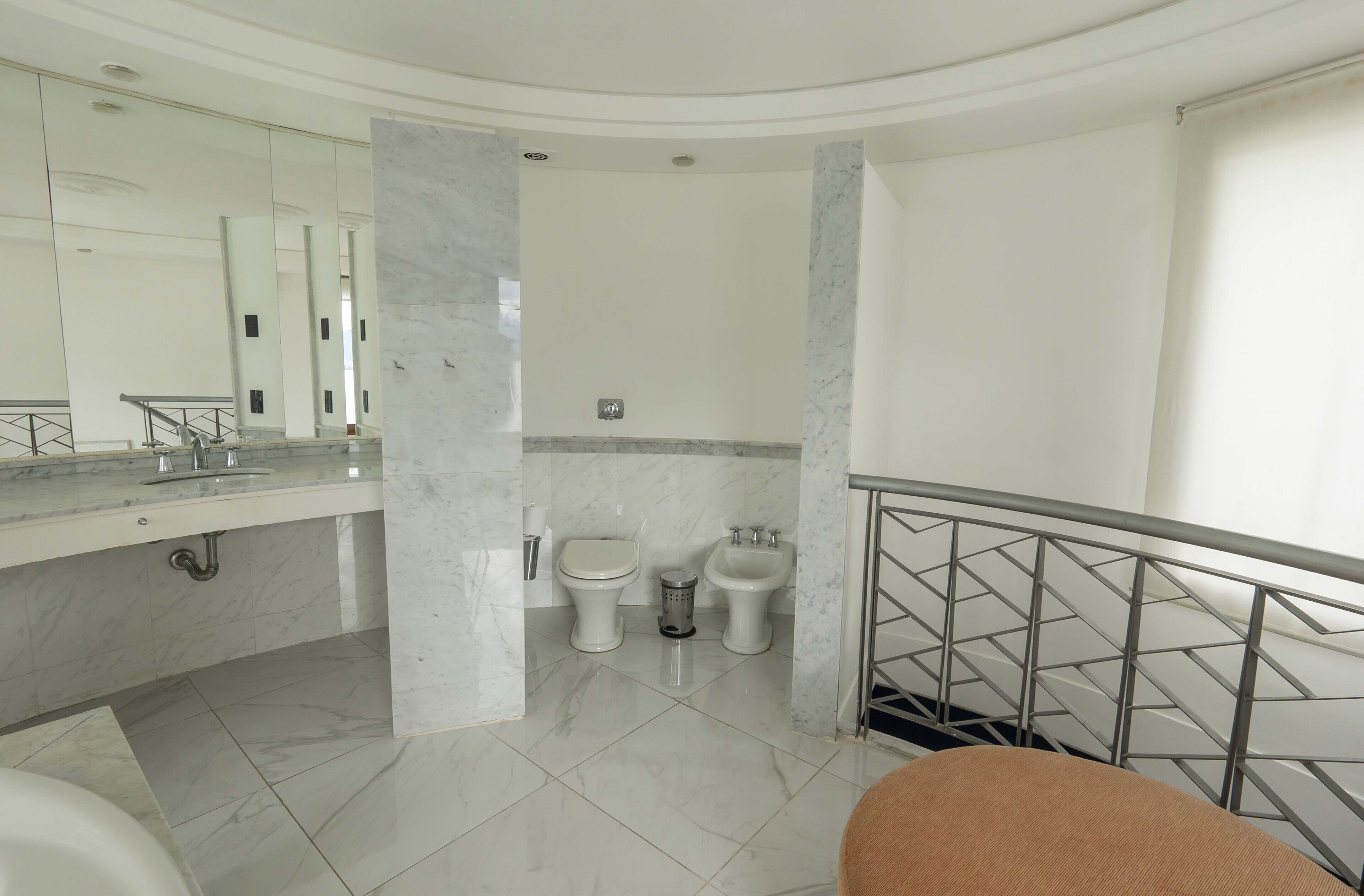 Un baño moderno con suelo de mármol, un espejo grande, un inodoro, un bidé y una bañera.