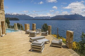 A wooden deck with lounge chairs and a pool, overlooking a lake with mountains in the background. - El Faro Boutique Hotel & Spa by DON (Villa La Angostura)