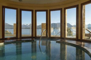 An indoor swimming pool with a clear view of mountains and a lake through large windows. - El Faro Boutique Hotel & Spa by DON (Villa La Angostura)