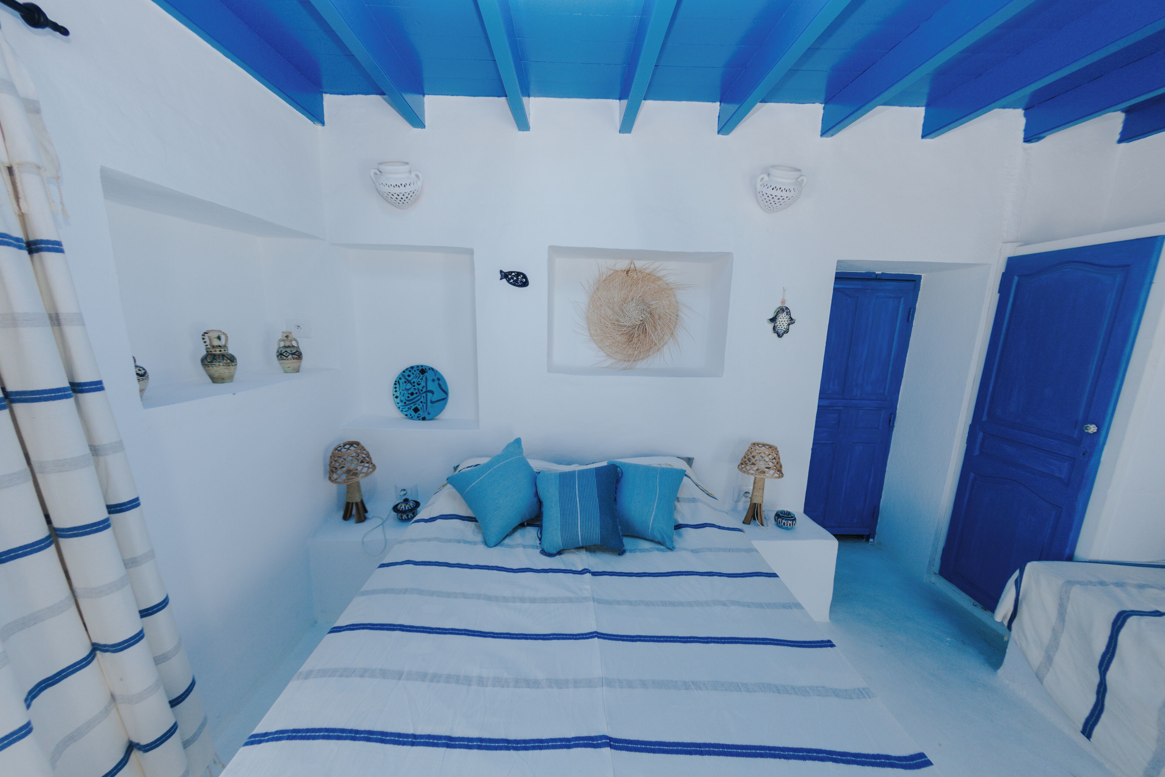 Une chambre à coucher avec un lit, une porte bleue et des objets décoratifs accrochés aux murs.