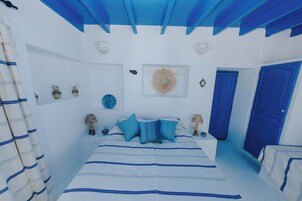Une chambre à coucher avec un lit, une porte bleue et des objets décoratifs accrochés aux murs.