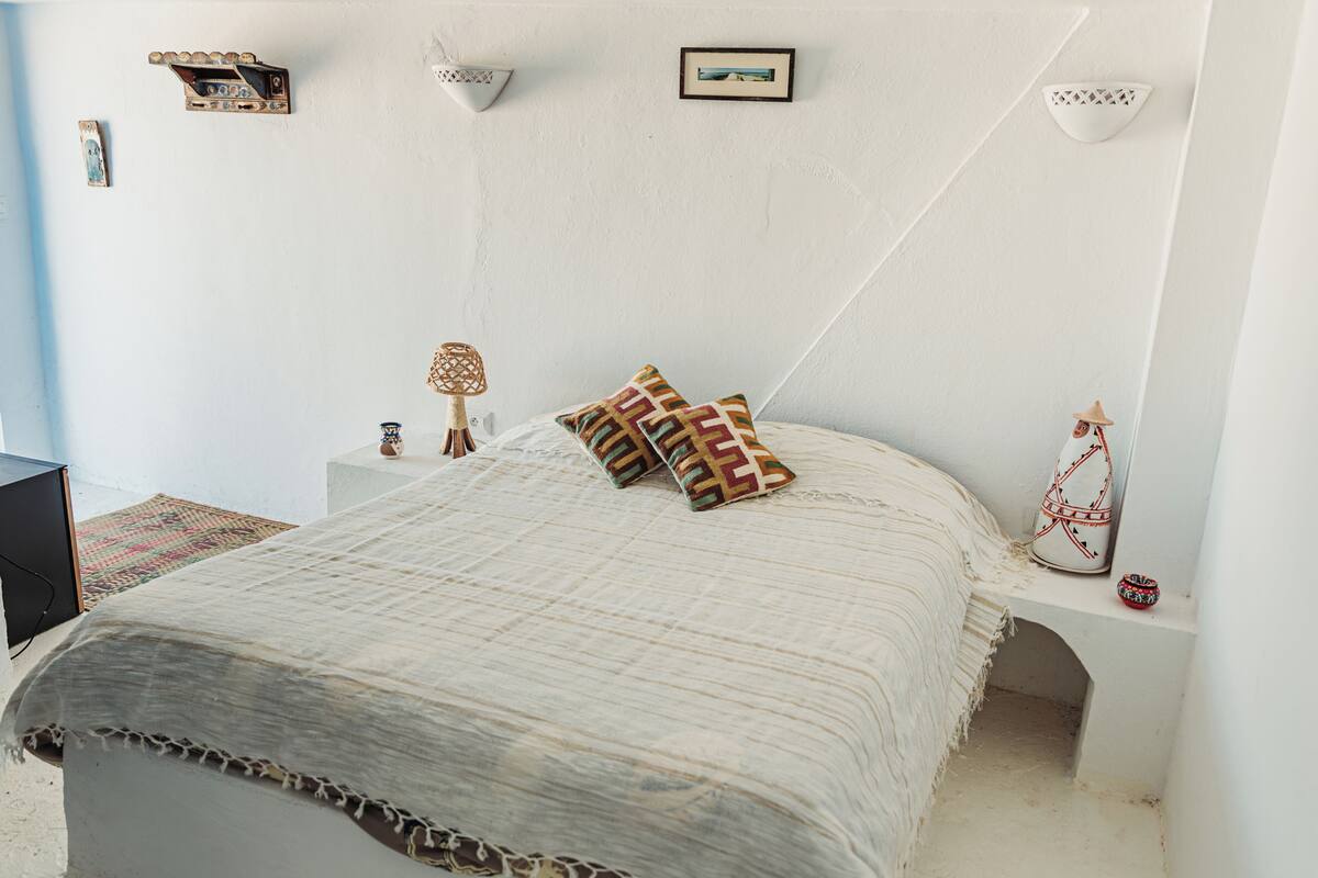 A bedroom with a bed, bedside tables, a lamp, and decorative items.
