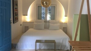 Ein Schlafzimmer mit einem großen Bett, einem kleinen Tisch, einer blauen Tür und einem dekorativen Wandbild.