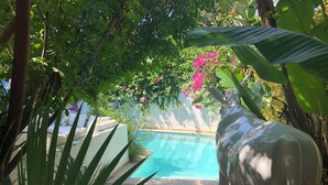Ein Poolbereich mit einer Statur eines Stiers, umgeben von üppiger Vegetation und blühenden Pflanzen.