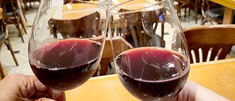 Dos personas sosteniendo copas de vino tinto.