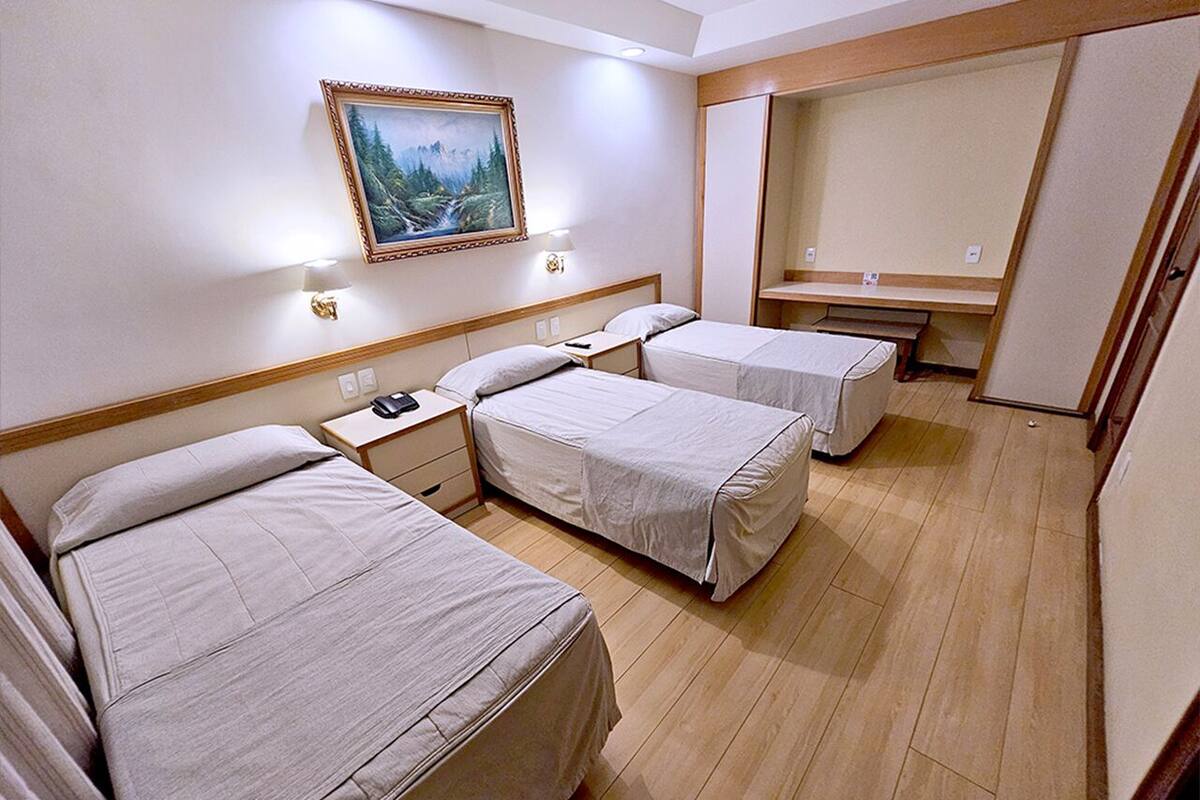 Ein Hotelzimmer mit zwei Betten, einem Nachttisch, einem Bild an der Wand und einem Spiegel.