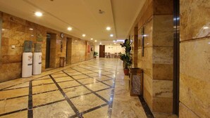 A spacious lobby with a marble floor, a reception desk, and potted plants. - Abraj Al Tayseer Tuwa Hotel (Makkah)