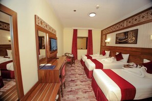Une chambre d’hôtel avec deux lits, un bureau, une chaise, une télévision et un miroir.