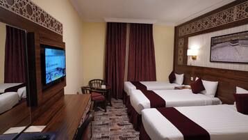 A hotel room with a TV, two beds, a desk, and a chair.