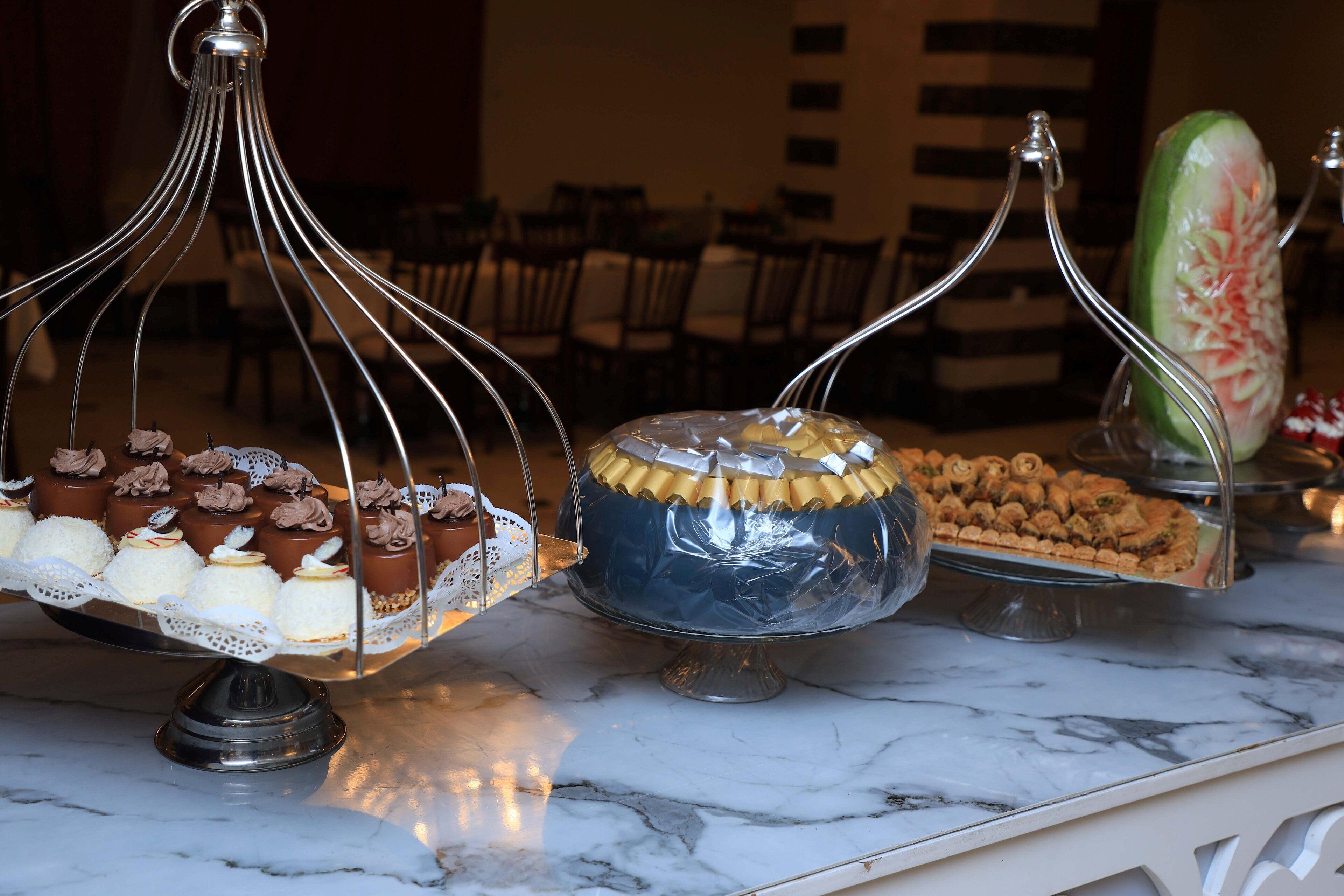 A marble countertop with various desserts displayed on stands.