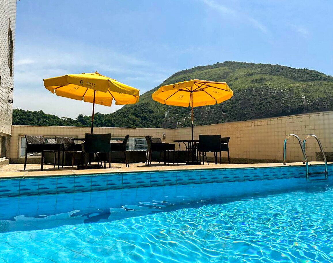 Una piscina al aire libre, sombrillas, sillones reclinables de piscina
