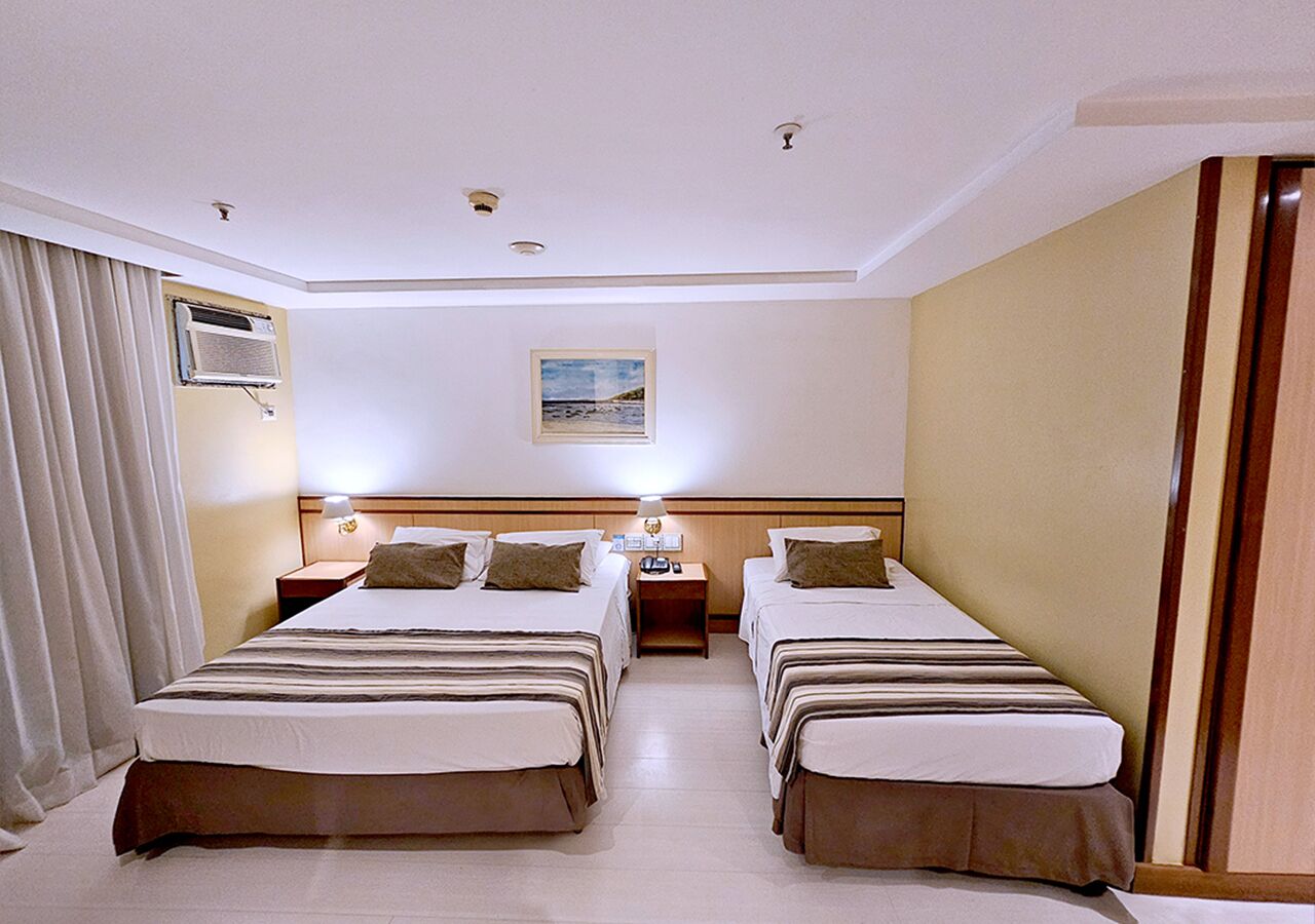 Une chambre d’hôtel avec deux lits, une table de chevet, une lampe et un appareil de climatisation.