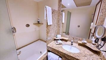 A bathroom with a bathtub, a sink, a mirror, and a towel rack.