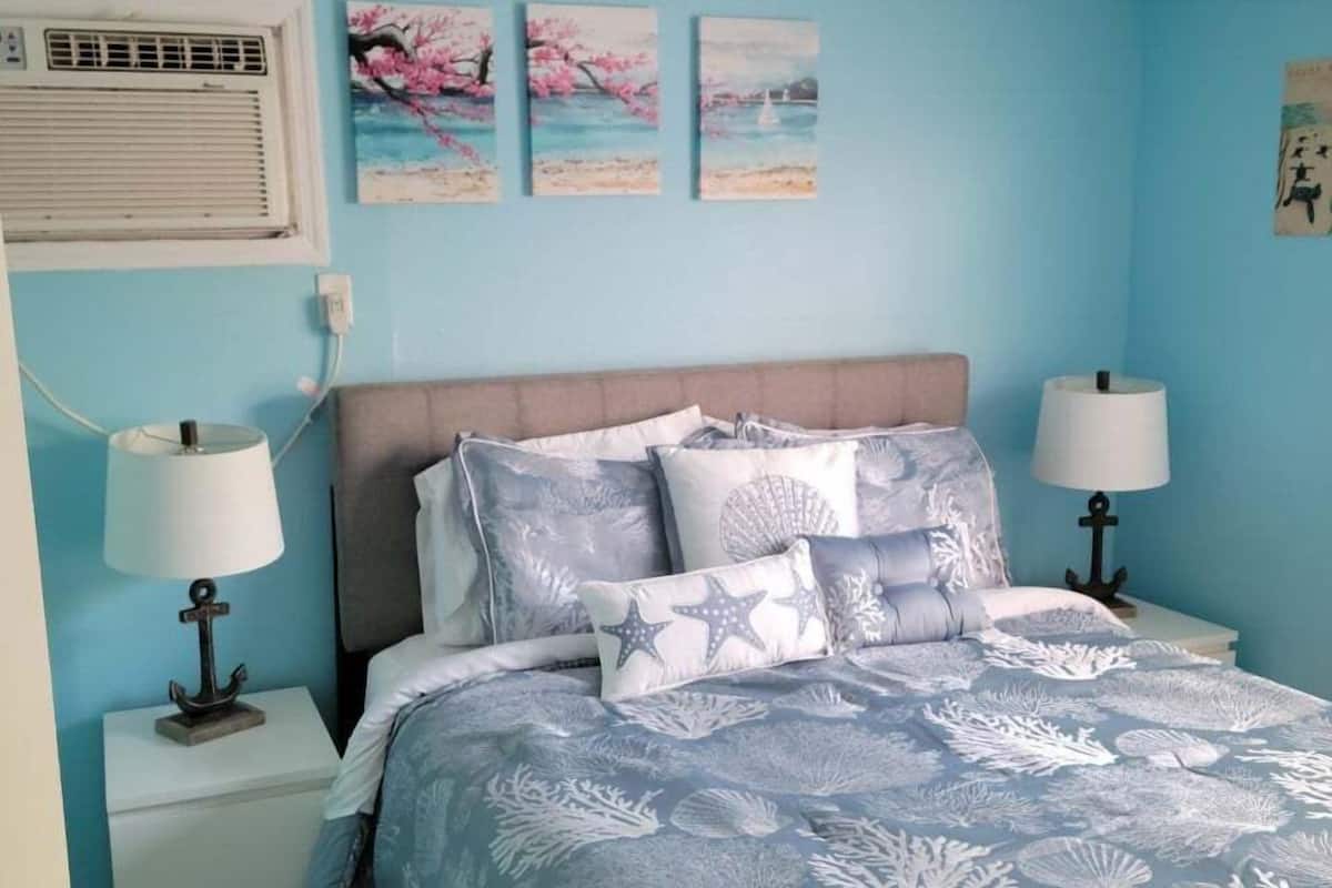 A bedroom with a bed, nightstands, and wall art.