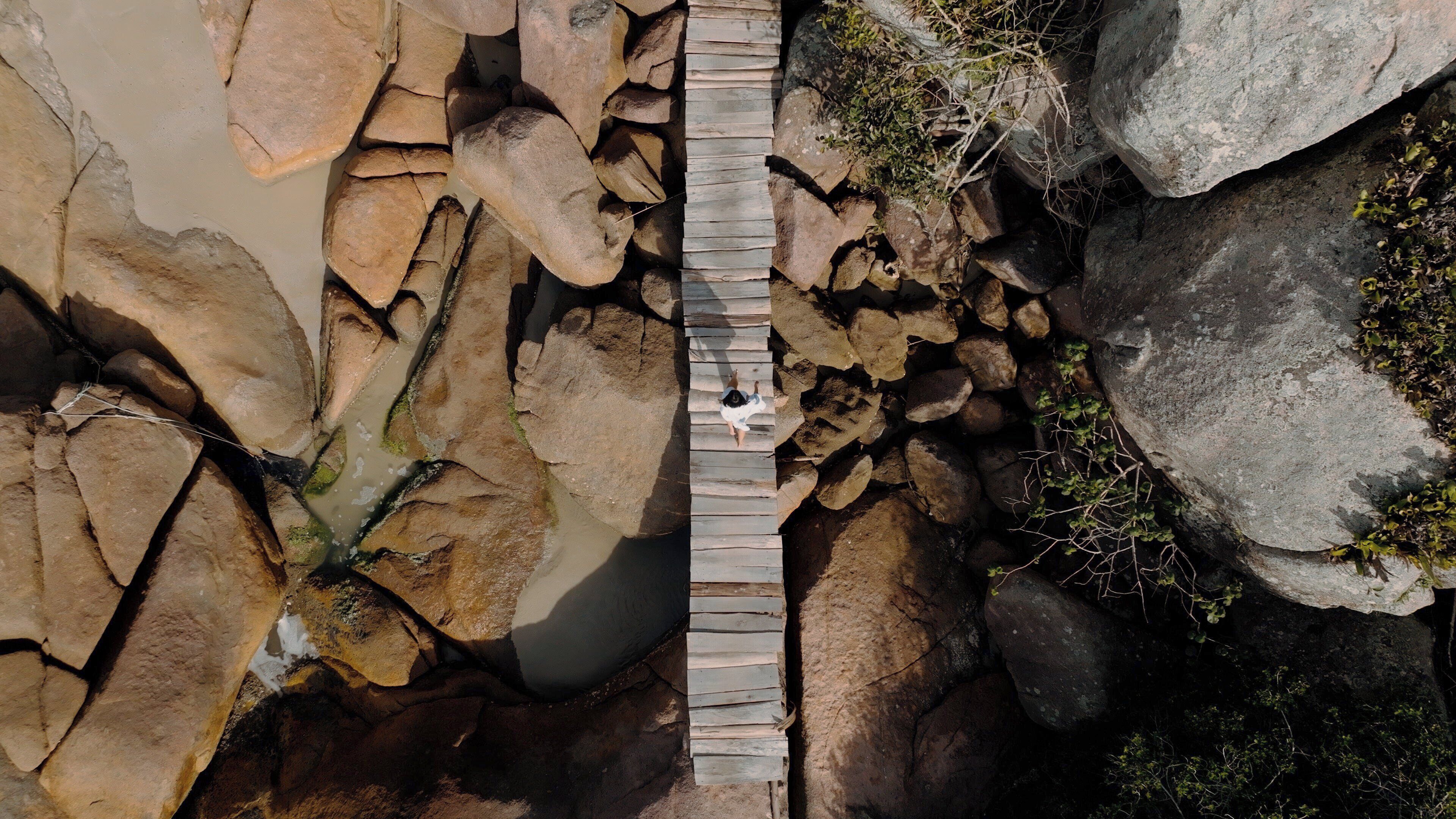 A wooden bridge over a rocky terrain with a person standing on it.