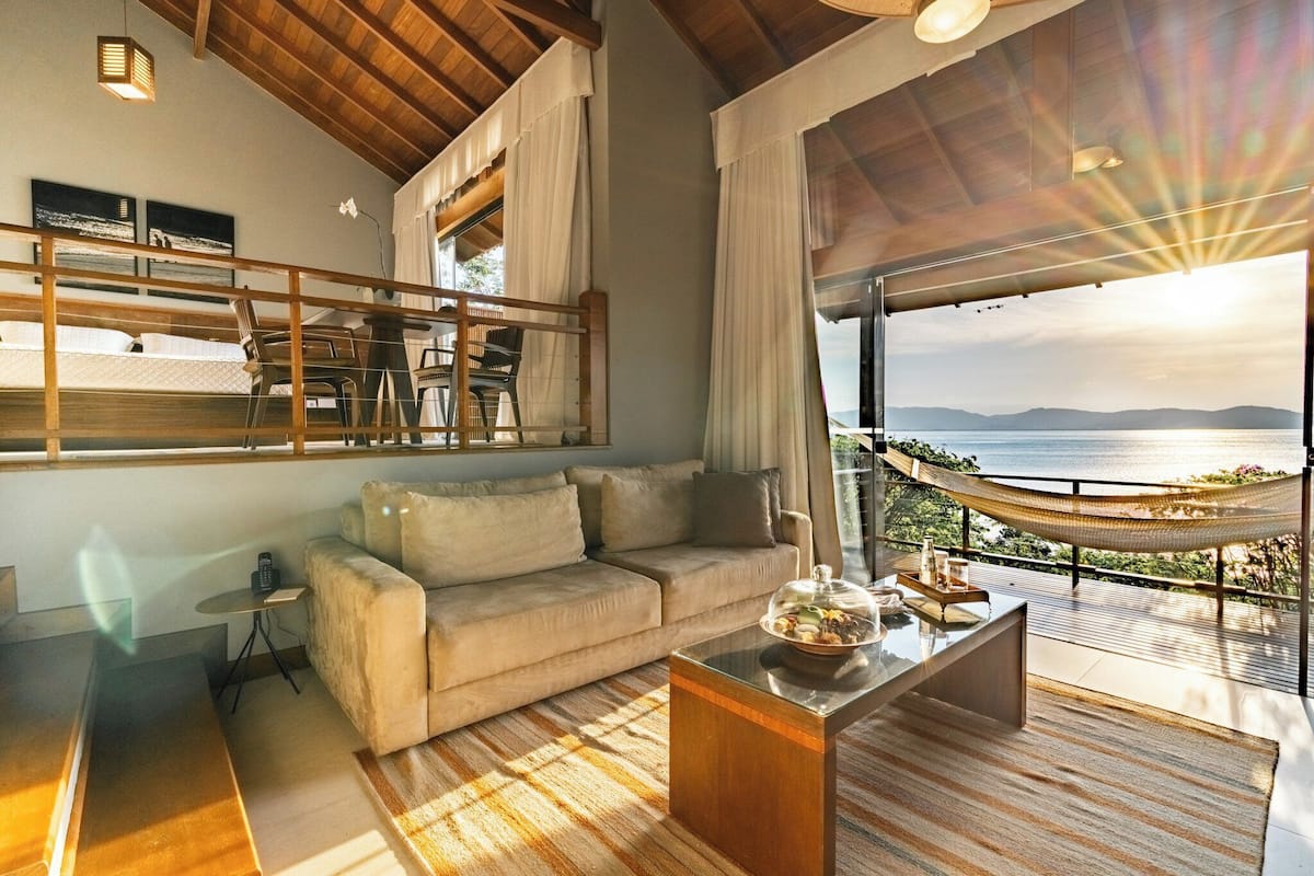 A modern living room with a sofa, coffee table, and a view of the sea.