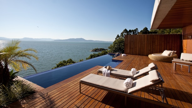 An infinity pool with wooden deck, lounge chairs, and a view of the sea. - Awasi Santa Catarina (Governador Celso Ramos)