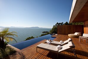 An infinity pool with wooden deck, lounge chairs, and a view of the sea. - Awasi Santa Catarina (Governador Celso Ramos)